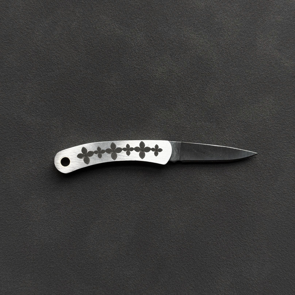 A small folding pocket knife with a silver handle featuring a row of black floral or cross-like cutouts, and a metal blade, displayed horizontally on a dark textured background.